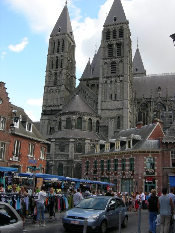 The outside of Tournai Cathedral with its Romanesque nave and soaring transept towers (dating to the 12th century), from the busy marketplace